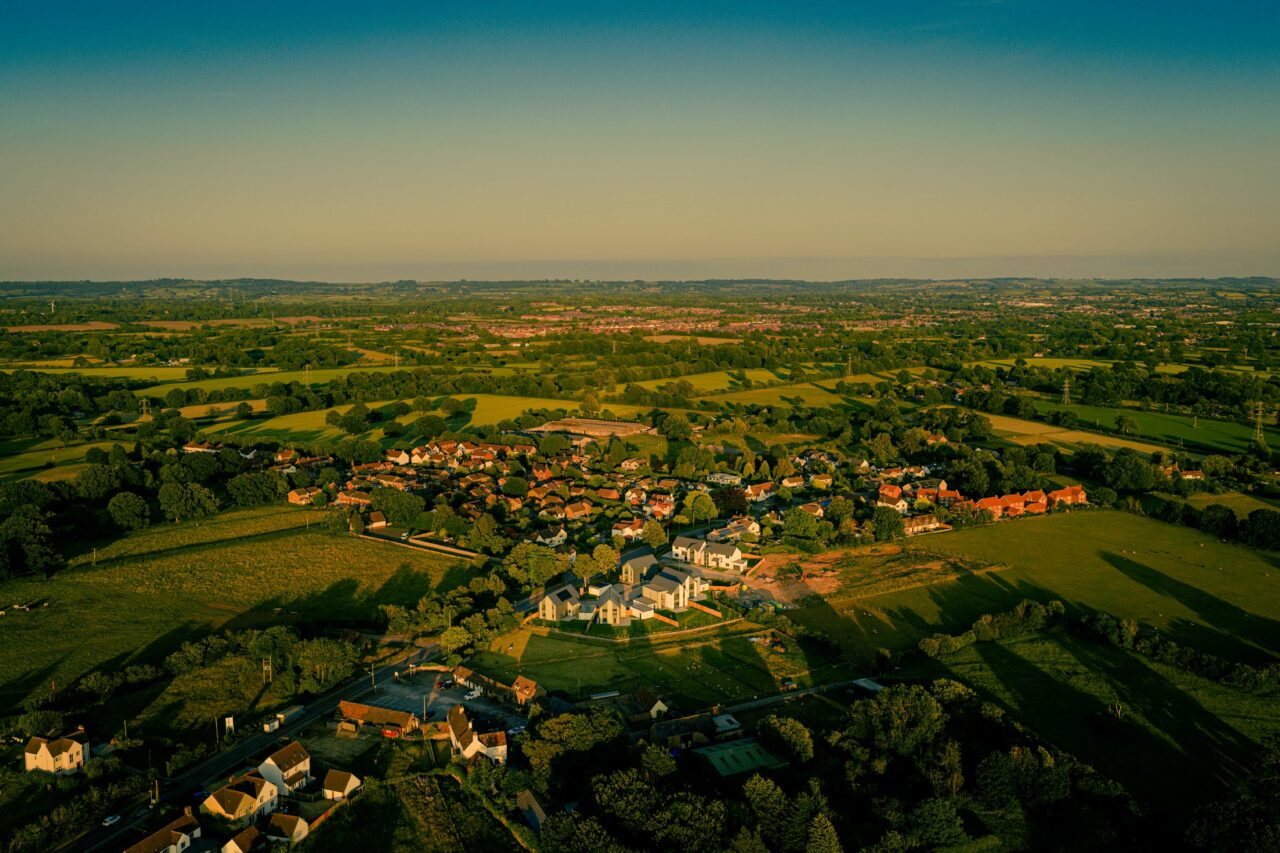 An aerial shot of a property development site in Rangeworthy, South Gloucestershire during golden hour in June 2025 facing away from the sun.