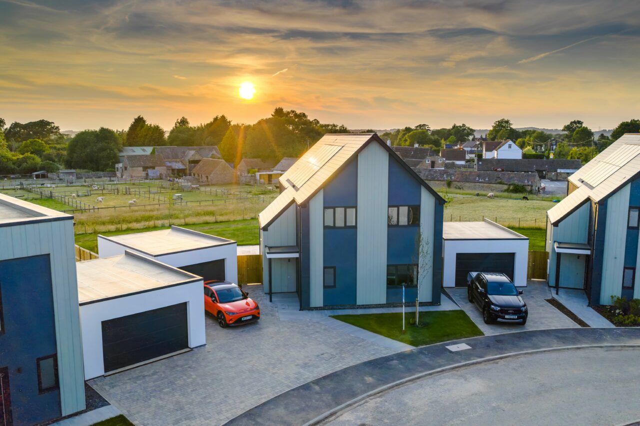 An elevated shot of a property at a property development site in Rangeworthy, South Gloucestershire during golden hour in June 2025, with the sunlight peaking out from behind the treeline and house.