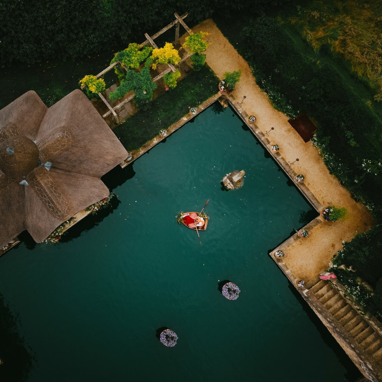 A top-down aerial shot of the bride and groom in a row boat on the lake at Euridge Manor