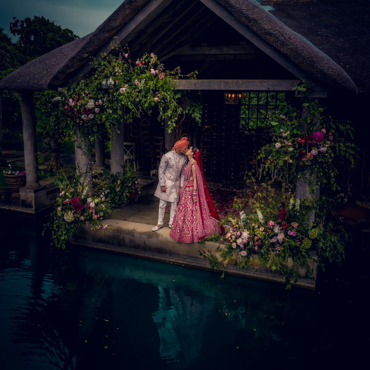 An aerial shot over water of the bride and groom at Euridge Manor at the dock kissing each other.